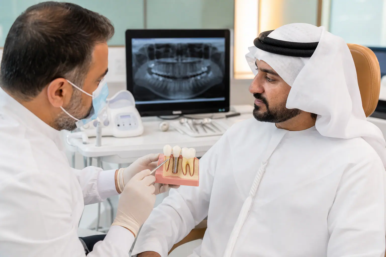 شرح إجراء زراعة الأسنان — طبيب أسنان مع مريض في عيادة أبوظبي