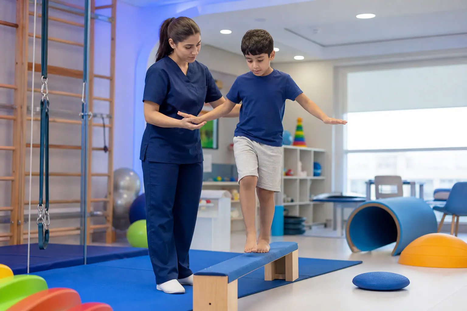 Cognitive and motor skills training - a child on a balance beam with an occupational therapist at Al Ahli Al Shamkha Center